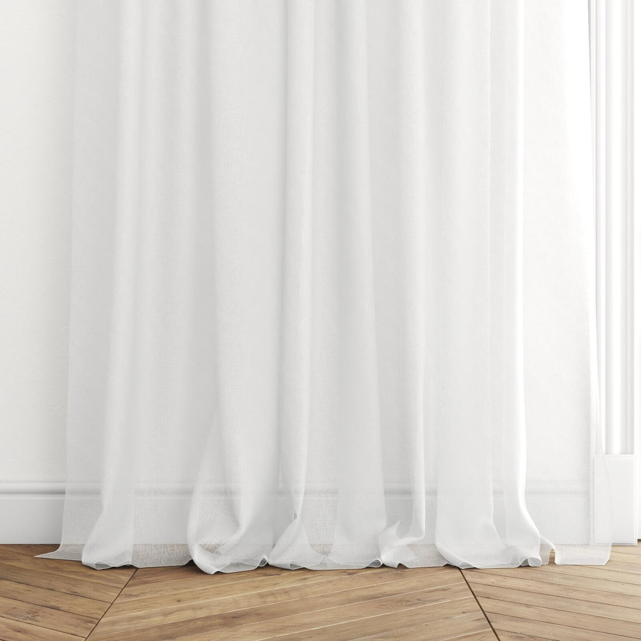 The hem of Whisper ecru semi-transparent curtains gracefully cascading onto a herringbone timber floor.